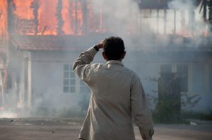 Man standing outside watching his house burn