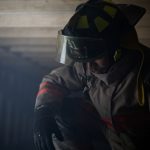 Firefighter kneeling at the scene of a fire he is upset